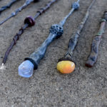seven homemade clay wands laying on cement