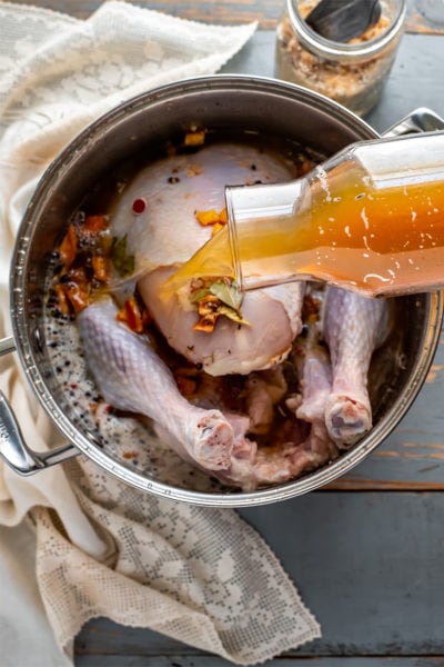 apple cider brine being poured over turkey in a large soup pot