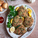 panko crusted turkey cutlets on a platter with parsley, sage and lemon wedges