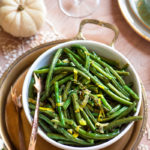 roasted green beans in a white bowl on a brass tray